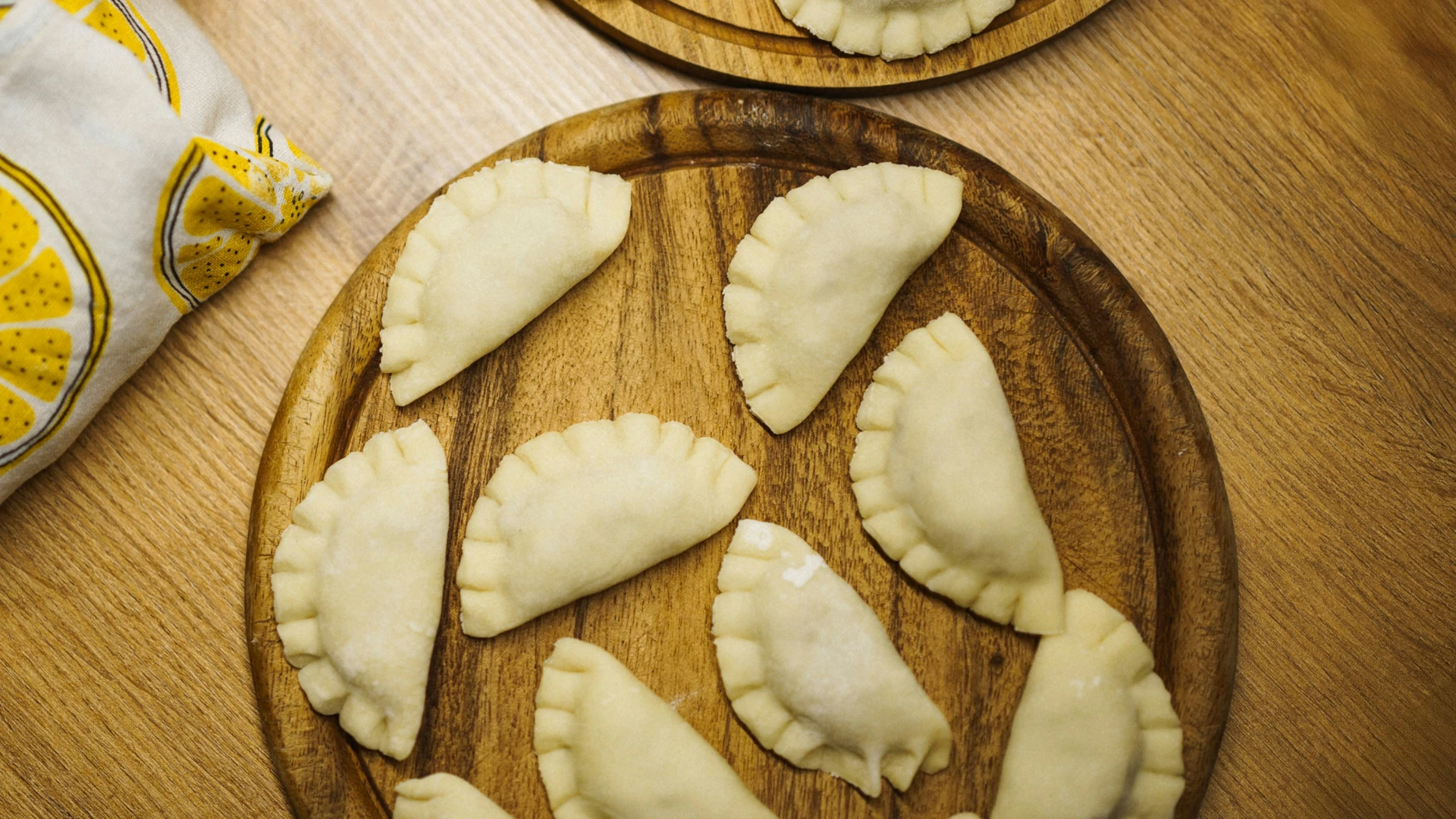 Drewniana deska ze świeżo przygotowanymi pierogami.