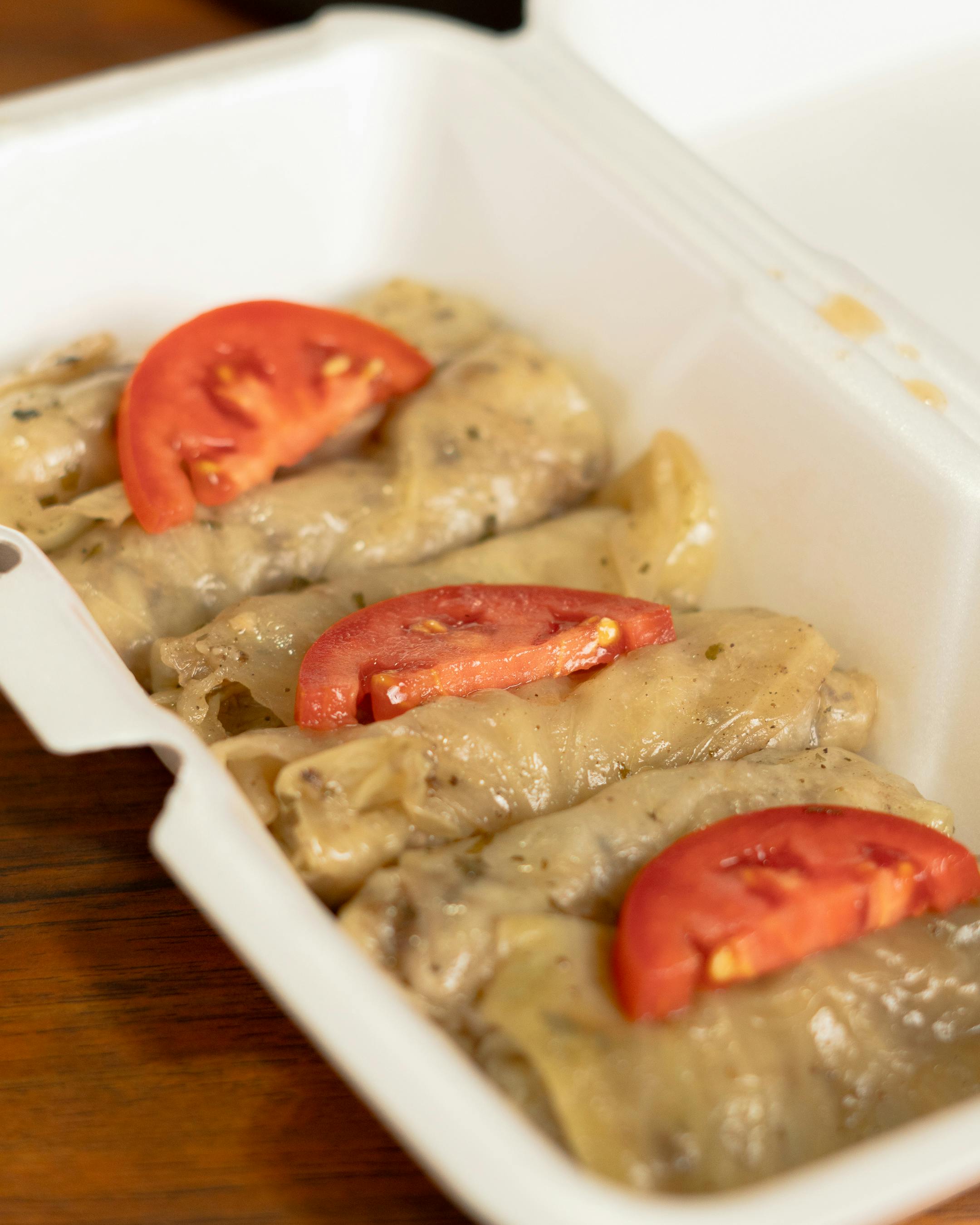 Gołąbki podane w pudełku na wynos, udekorowane plasterkami pomidora